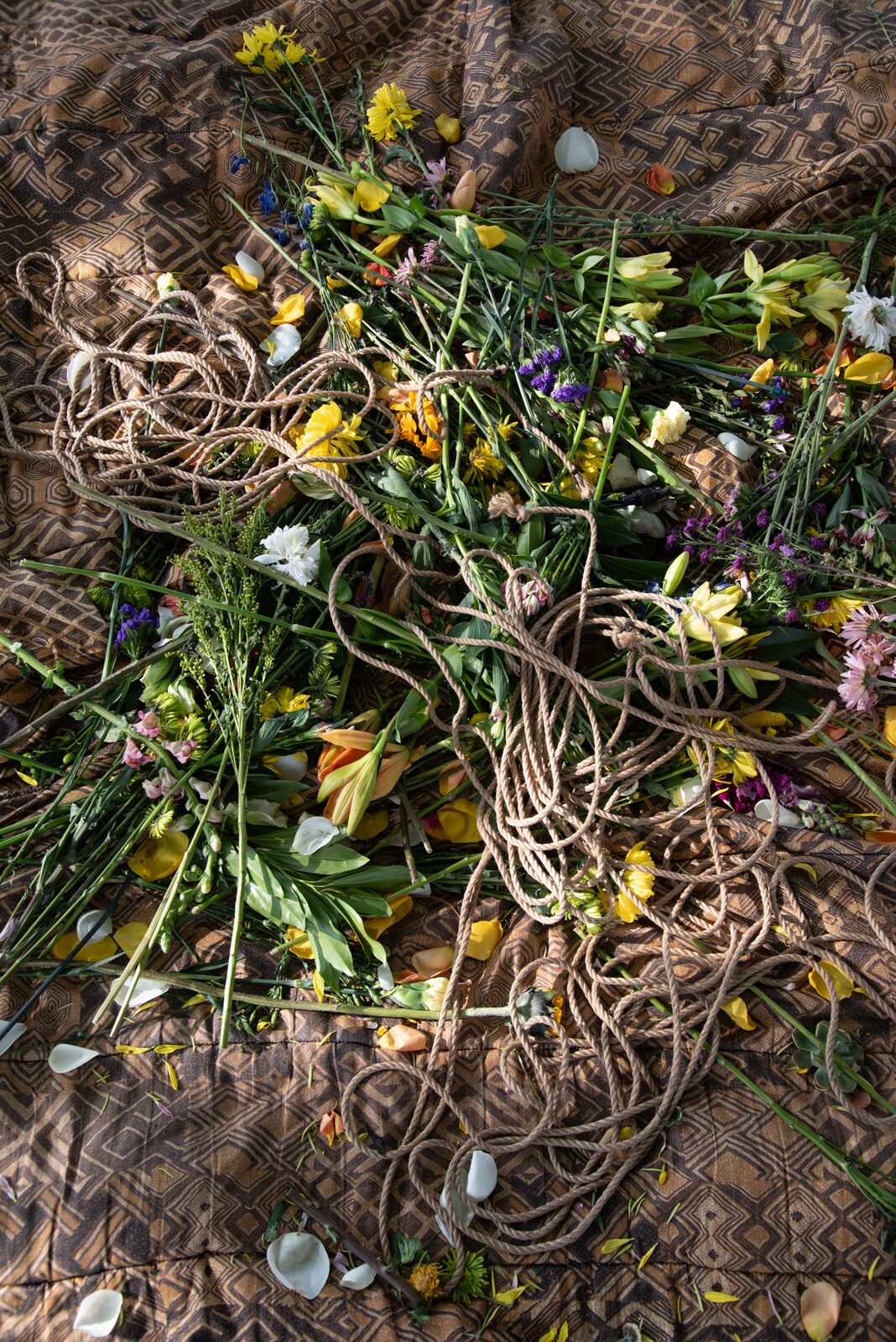 Rope coiled on a quilt; flowers waiting in a basket.