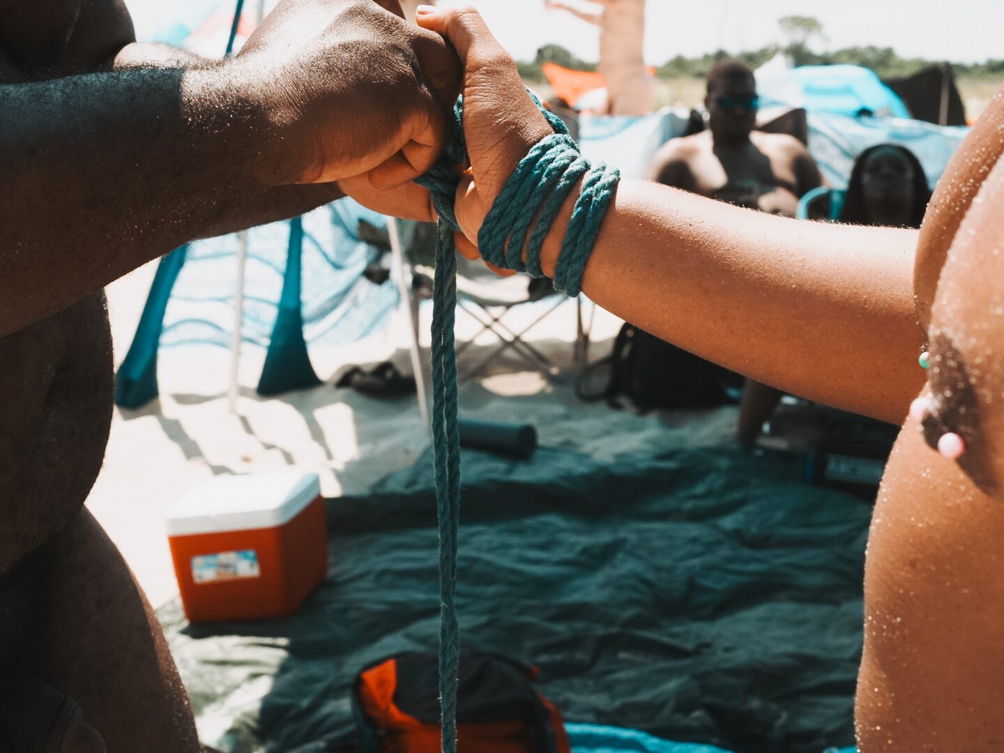 Red rope being tied, hands mid-knot.