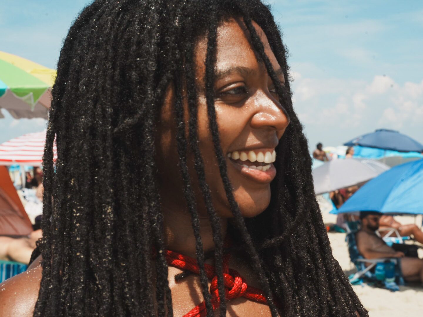 A face turned to the camera, laughing, beach behind.
